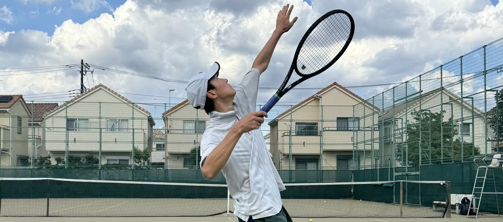 One of your hosts mid-serve on an omni court, racket up and eyes on the ball.